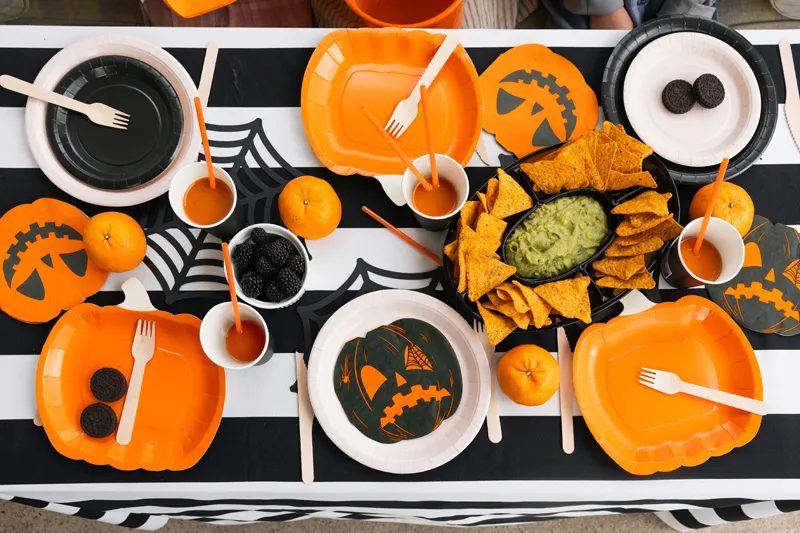 Goûter d'Halloween : assiettes citrouilles orange, sets toile d'araignée et nappe rayée noir et blanc