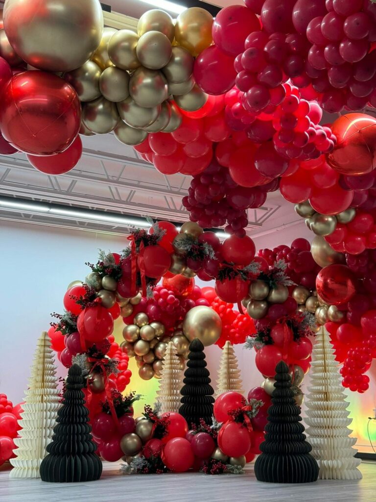 Arche de ballons rouge et or et sapins décoratifs pour une fête de Noël