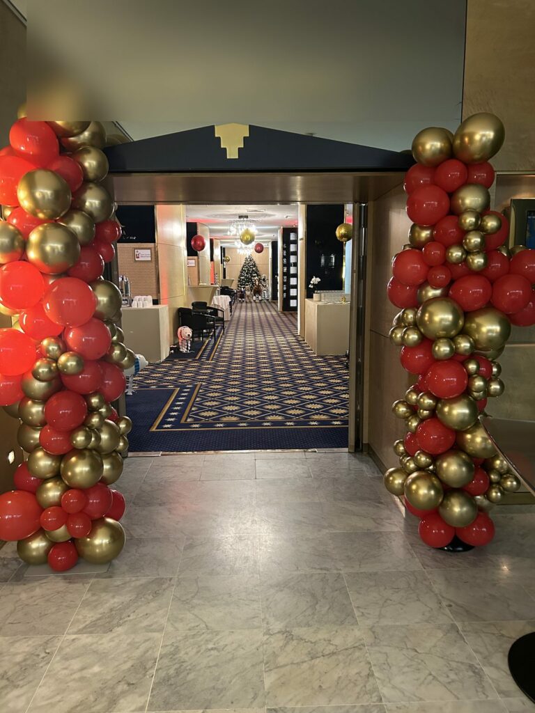 Entrée de salle décorée de colonnes de ballons rouge et or pour la Saint-Nicolas